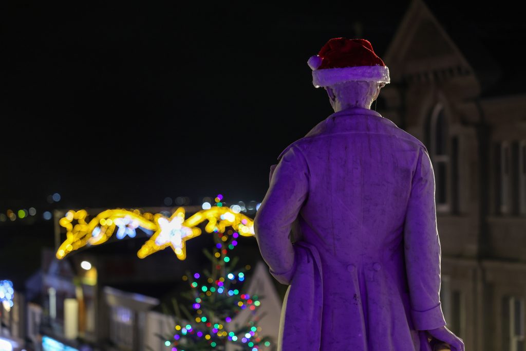Humphry Davy Statue wearing a Christmas hat looking down Market Jew Street at the Christmas Lights