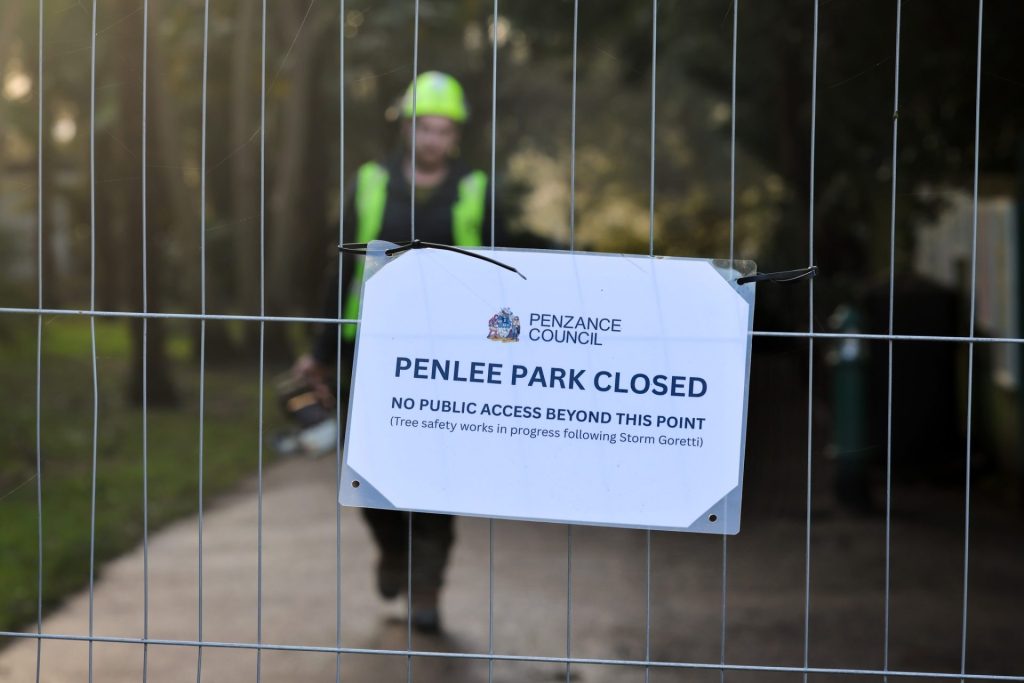 Closure sign on fencing at Penlee Park with a workpseron in high vis in the background