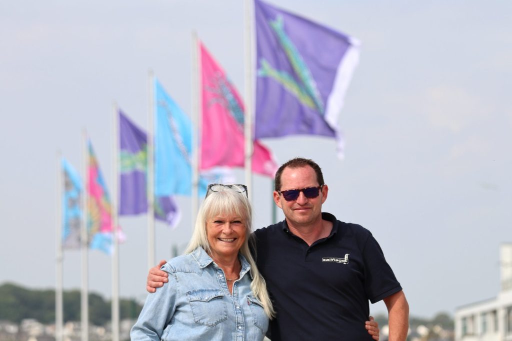 Artist Stevie McCrindle and Vaughan from Sailflags in front of the new flags on the prom
